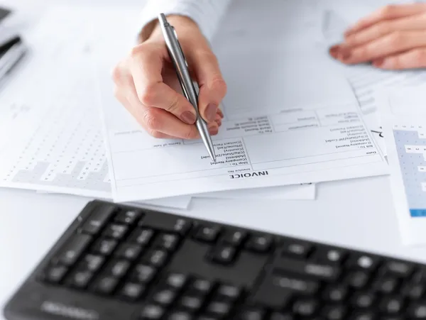 A person writing on paper next to a keyboard.