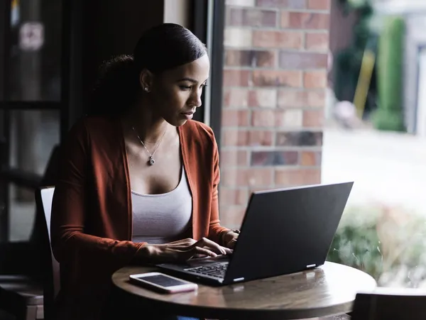 A woman sitting at a table using her laptop.